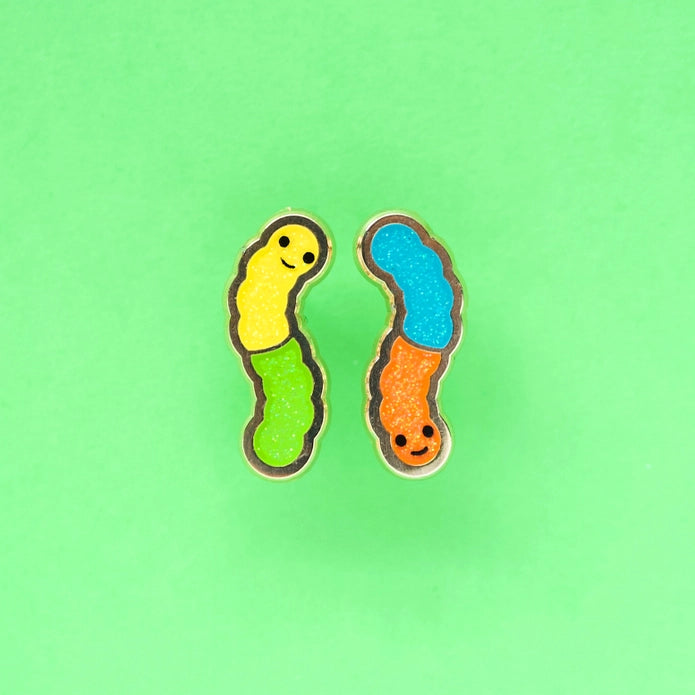 Gummy worm earrings against a green background.