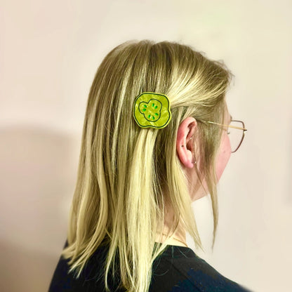 Blonde model with pickle clip in their hair against a light background.