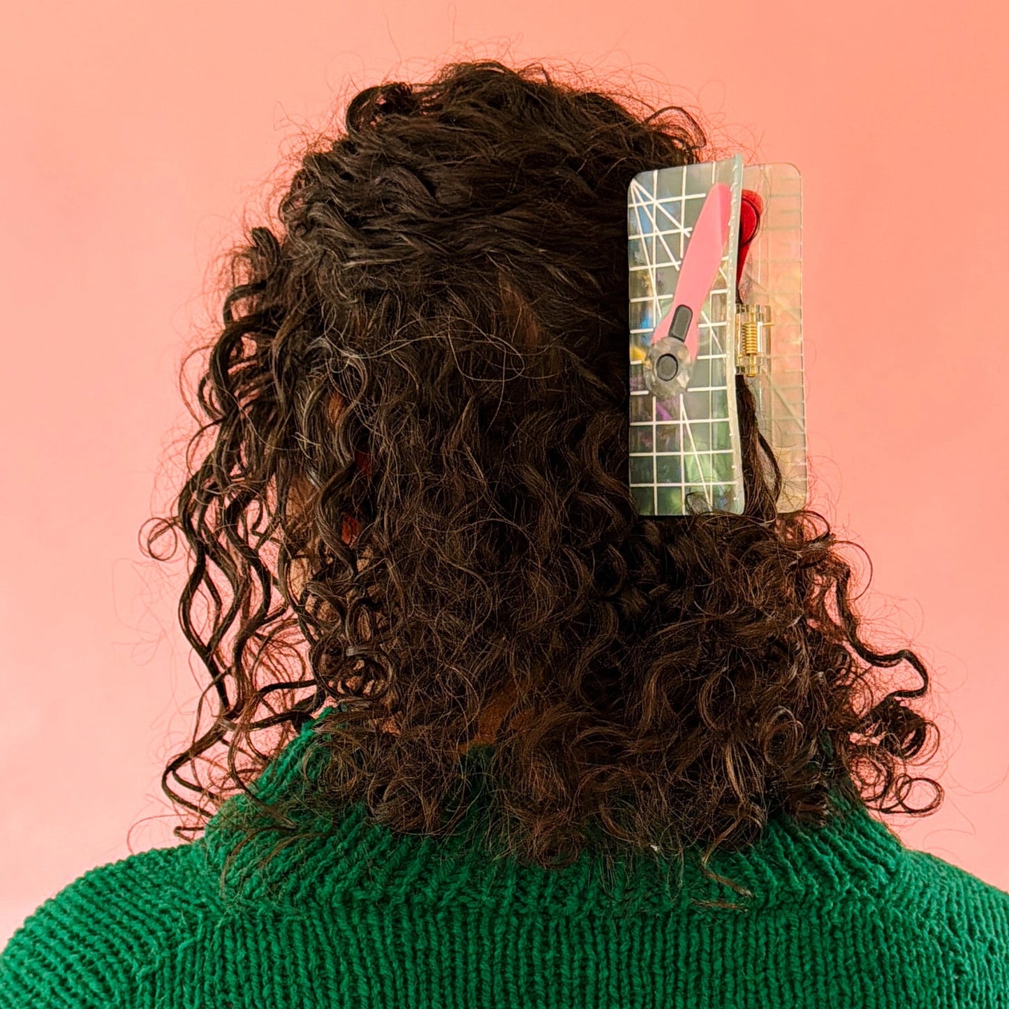 Brunette model wearing hair claw against a pink background.