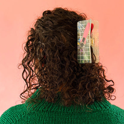 Brunette model wearing hair claw against a pink background.