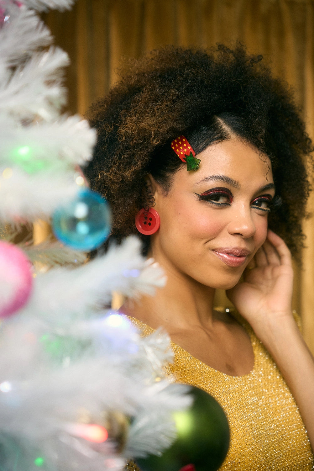 Model wearing strawberry candy hair clip behind a white Christmas tree against a yellow background.
