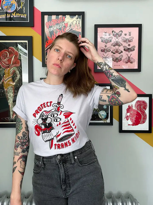 Model showing front of shirt against a gallery wall of tattoo styled artwork.