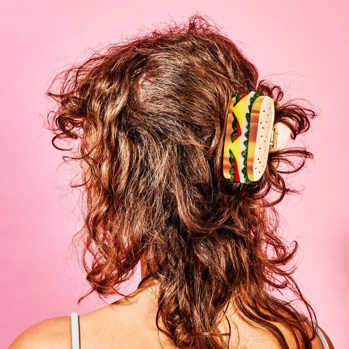 Brunette model with sandwich hair claw against a pink background.