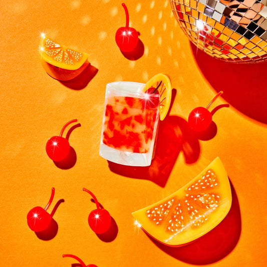 Hair claw shown against an orange background with orange slice hair claws, and cherries with a disco ball in the upper right hand corner.