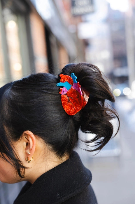 Dark haired model wearing heart hair claw against a light background.