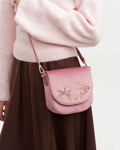 Model wearing pink saddle bag at their side against a white background.
