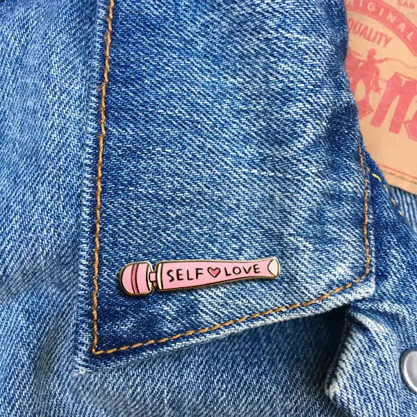 Pink vibrator with 'Self Love' text on a blue denim jacket collar.