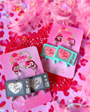 Black and white, and technicolor earrings on pink earring cards