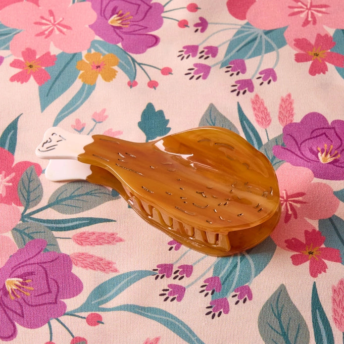 Drumstick hair claw laying flat on a floral background.