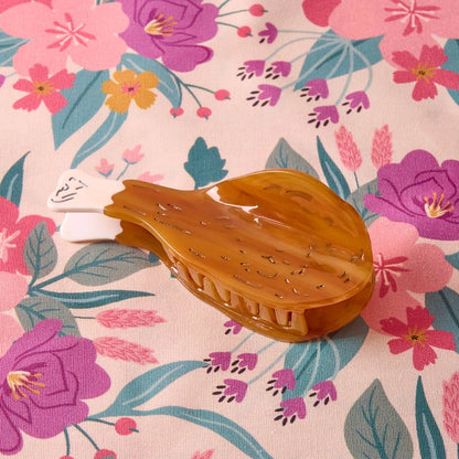 Drumstick hair claw laying flat on a floral background.