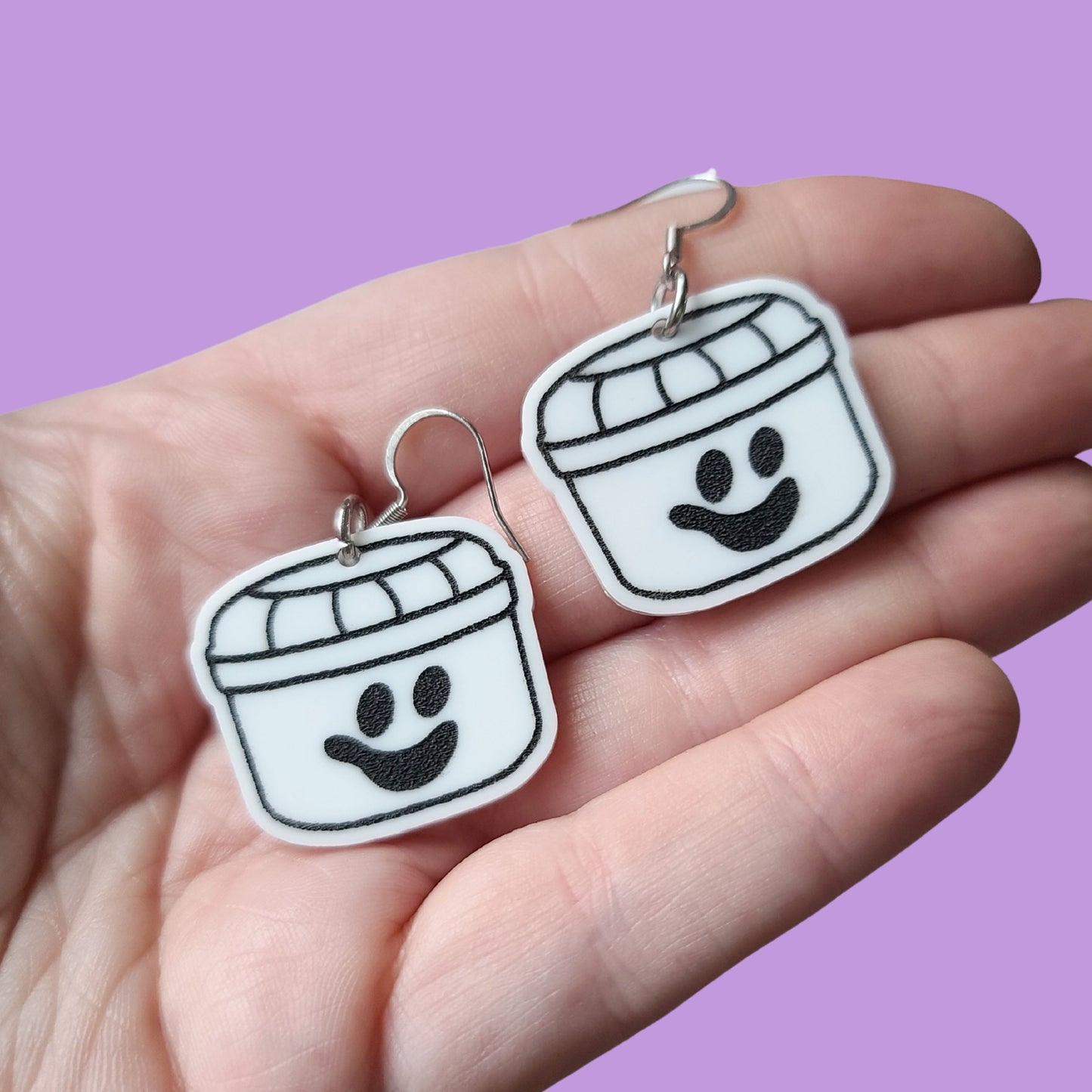 Hand holding earrings against purple background