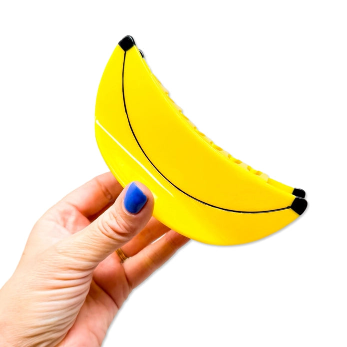 Hand holding banana hair claw against a white background.