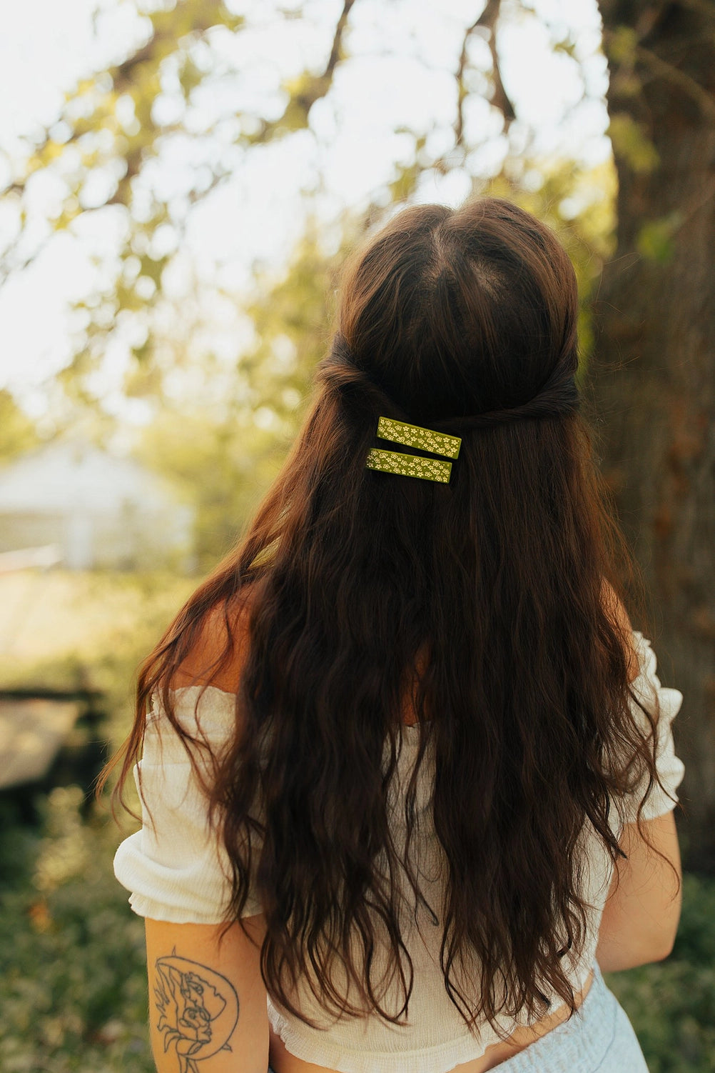 Brunette model wearing both hair clips against a wooded background.