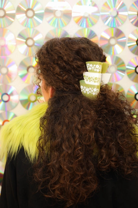 Model with brown, curly hair wearing the hair claw against a iridescent CD background.