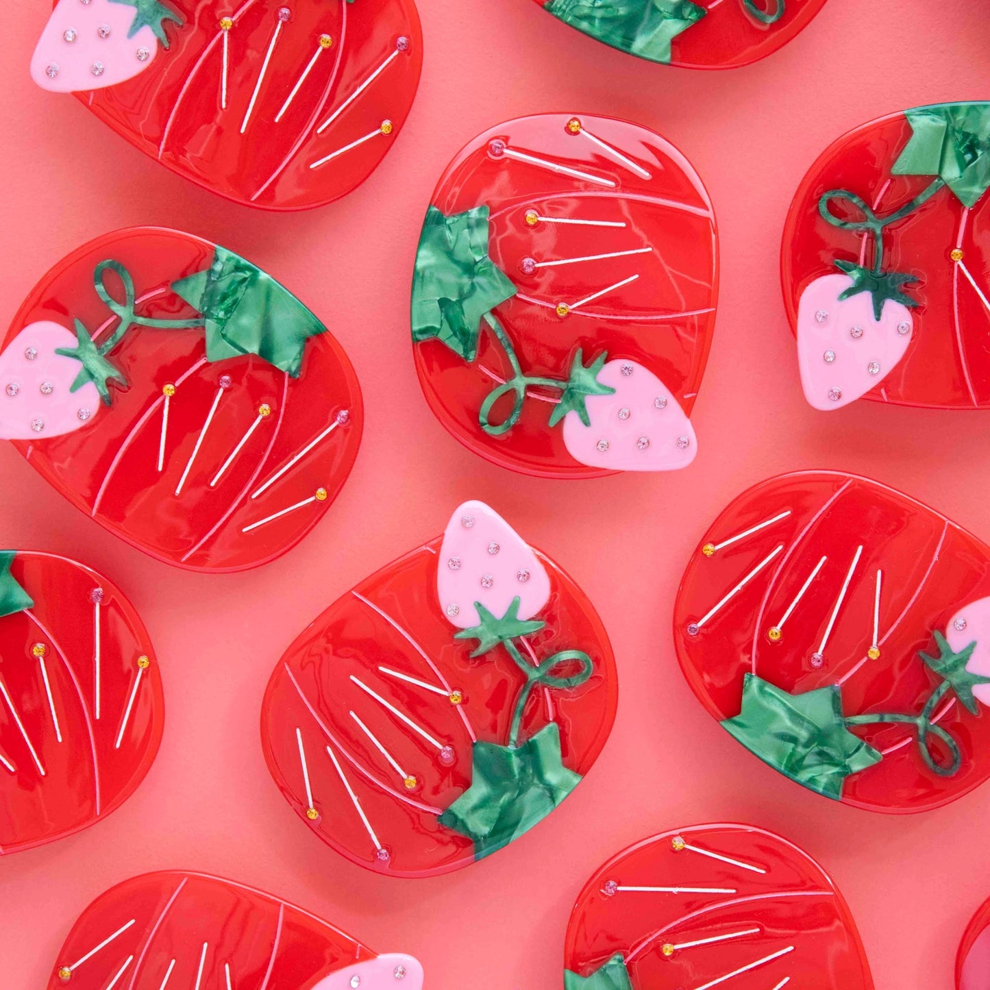Lot of red tomato pin cushions against a pink background.