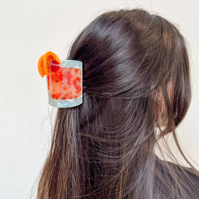 Hair claw in the hair of a model with dark brown hair against a white background.