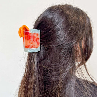 Hair claw in the hair of a model with dark brown hair against a white background.