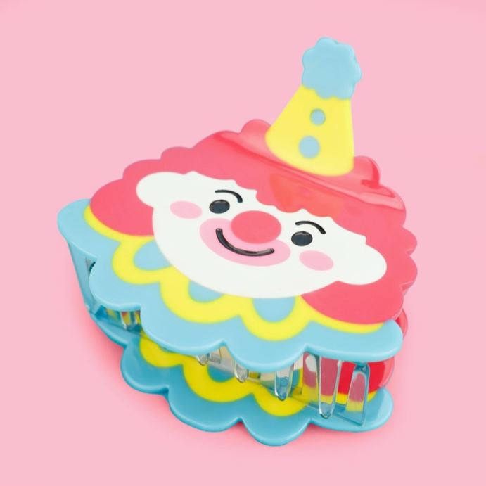 Circus Clown hair claw on it's side against a pink background.