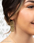 Close up of model wearing earring against a light background