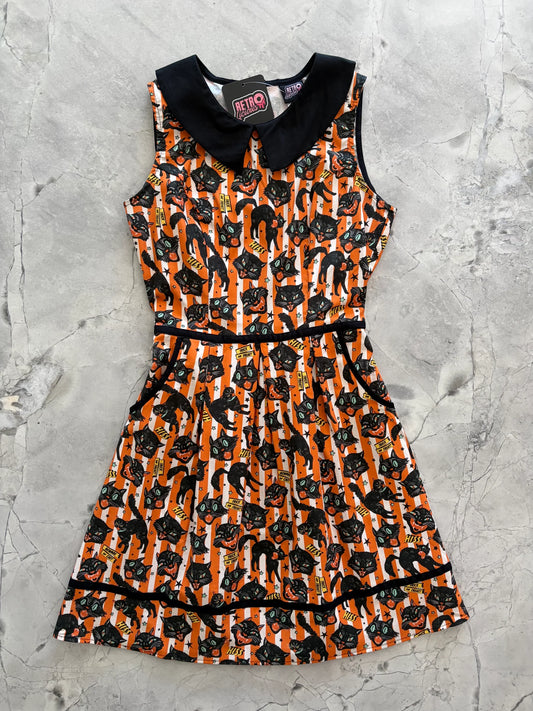 Front of orange, black, and white dress against a light concrete background.