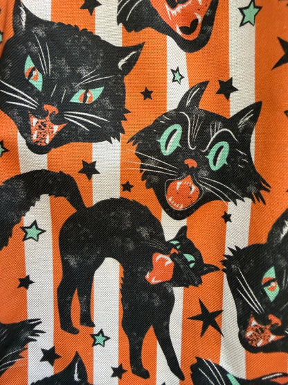Close up of the black retro styled Halloween cats on an orange and white striped background.