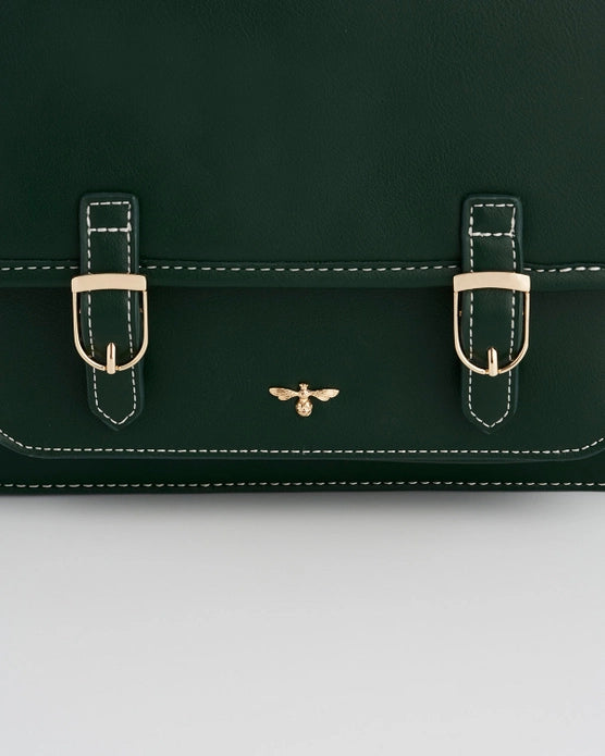 Close up of the dark green purse's gold buckles on the front of the purse and an insect logo.