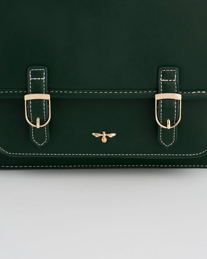 Close up of the dark green purse's gold buckles on the front of the purse and an insect logo.