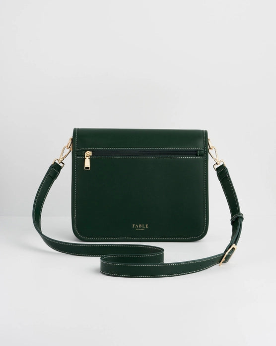 Back of dark green purse with zipper on back against a white background.