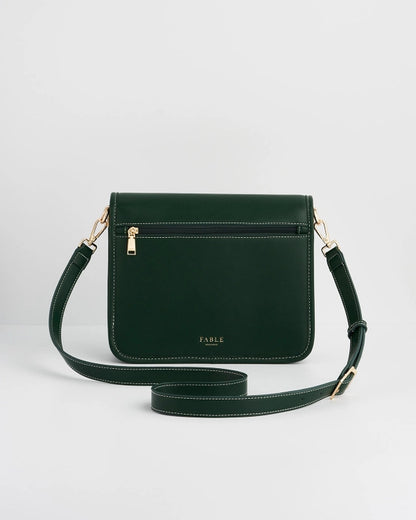Back of dark green purse with zipper on back against a white background.