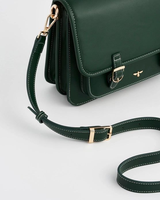 Close up of dark green strap with gold buckle accents against a white background.