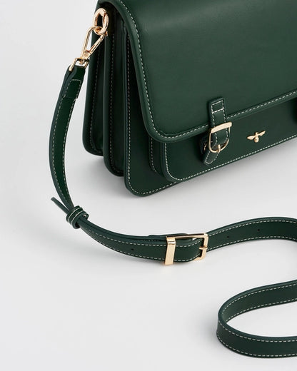 Close up of dark green strap with gold buckle accents against a white background.