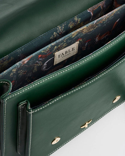 Interior of dark green purse with dark blue fabric, red foxes, a vintage style moon, birds, and foliage.