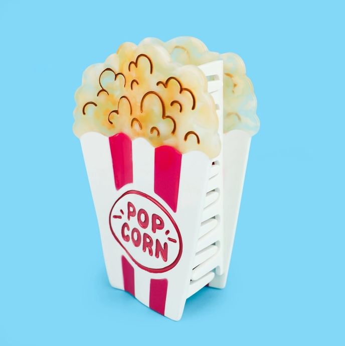 Red and white striped popcorn bucket hair claw against a blue background at a slight angle.