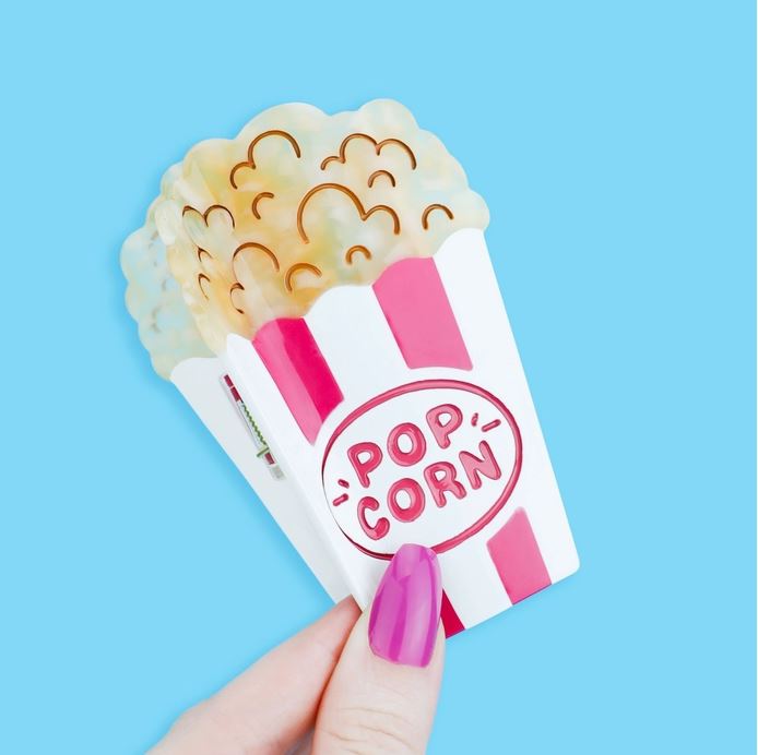 Red and white striped popcorn bucket hair claw against a blue background.