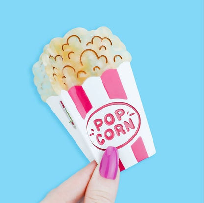 Red and white striped popcorn bucket hair claw against a blue background.