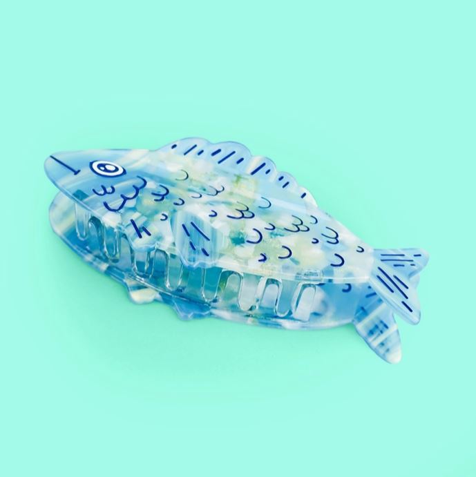 Blue sardine hair claw on it's side against a blue background.