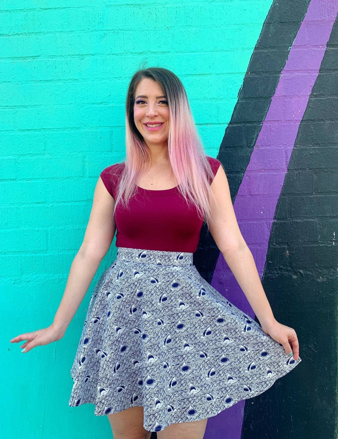 Full length model showing top paired with a light skirt against a colorful background