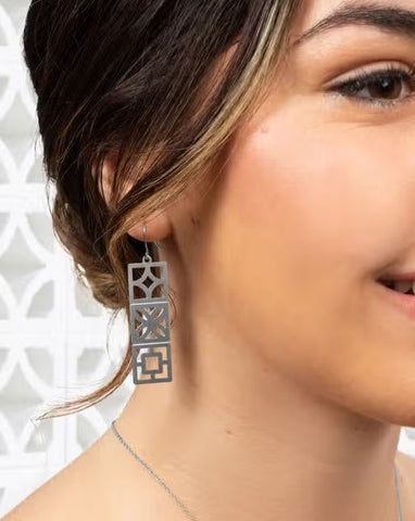 Close up of model wearing earrings against a light background