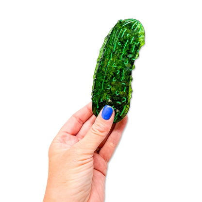 Hand holding green pickle hair claw against a white background.