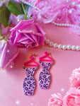 Earrings against pink background with floral and feather accents