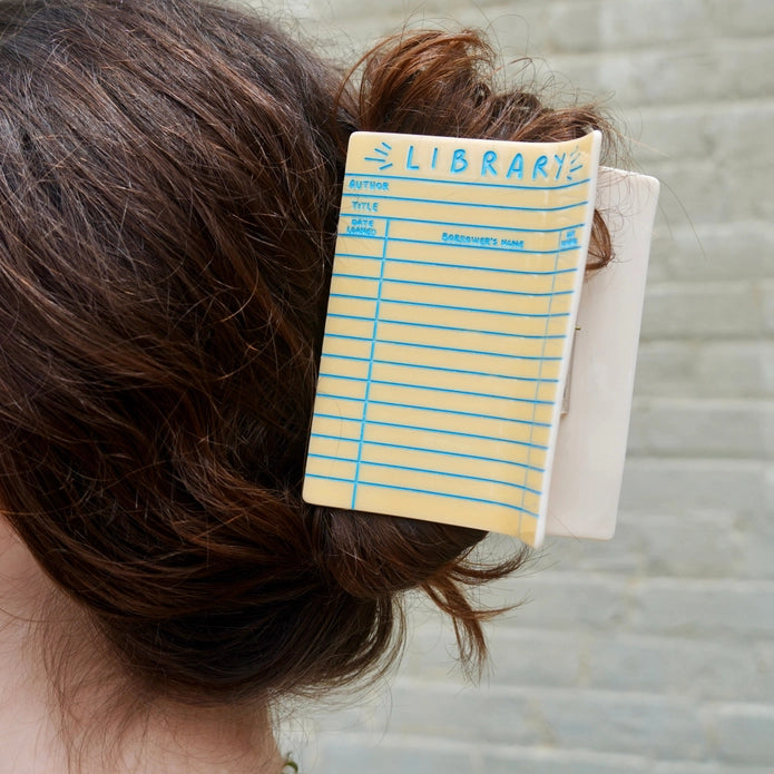 Brunette model wearing library card hair claw against a light background.