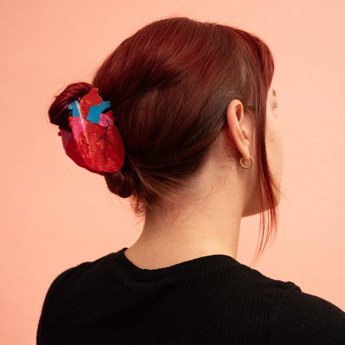 Red haired model wearing heart hair claw against a light background.