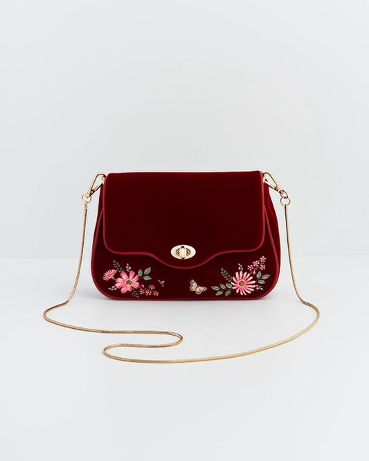 Front of red velvet purse with gold chain in front of the purse against a white background.