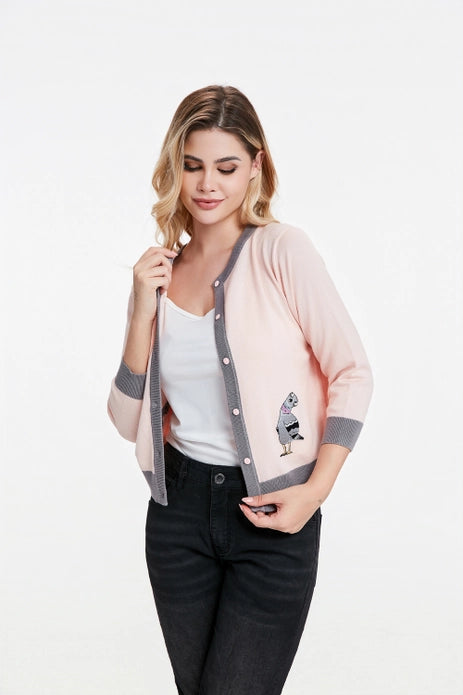 Woman wearing pigeon cardigan with front unbuttoned against a white background.