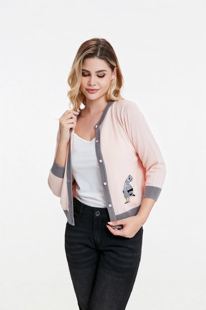 Woman wearing pigeon cardigan with front unbuttoned against a white background.