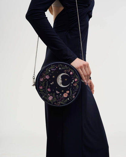 Model in a dark dress wearing the purse at their side against a white background.