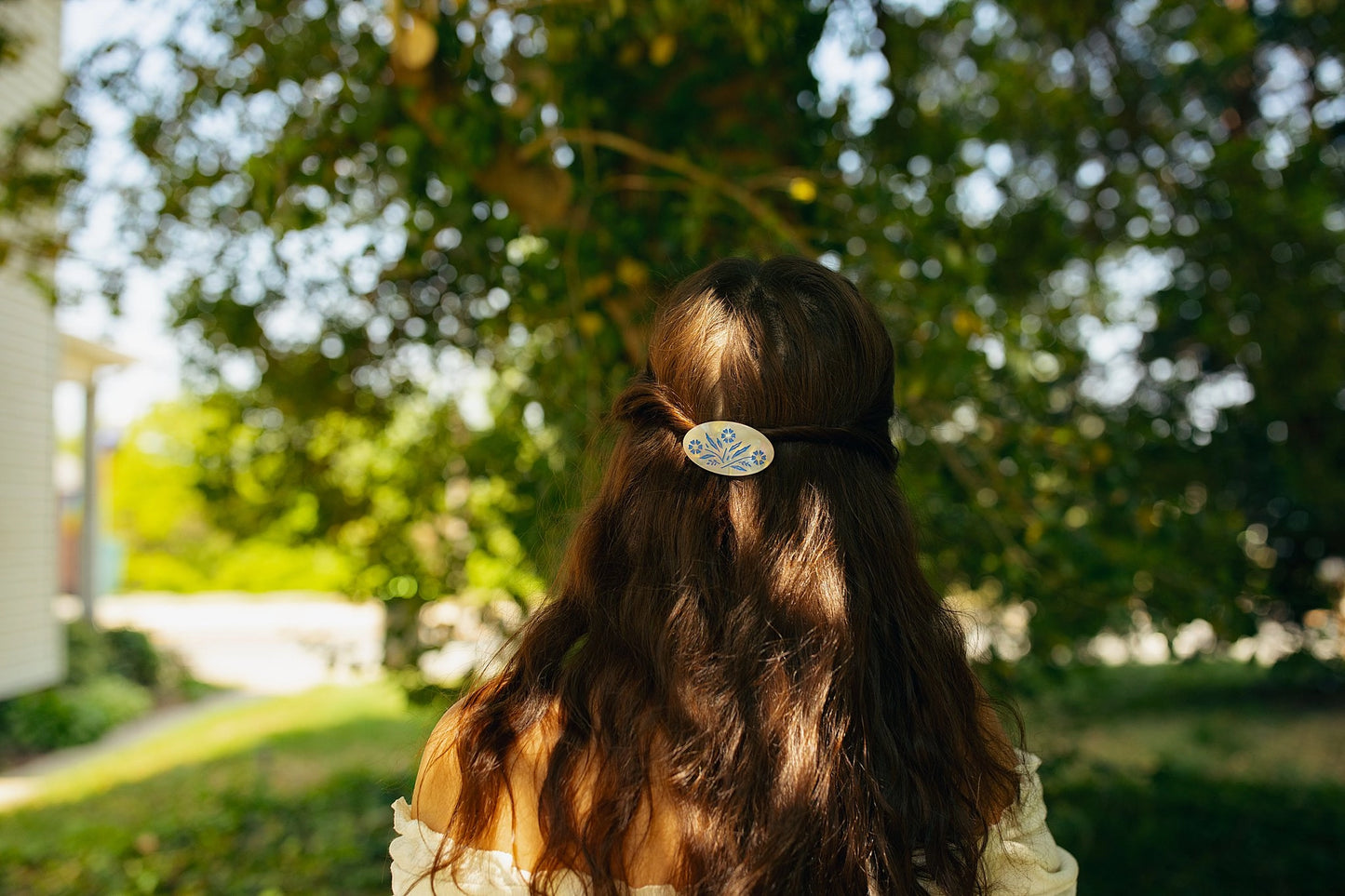 Brunette model wearing hair clip against a wooded background.