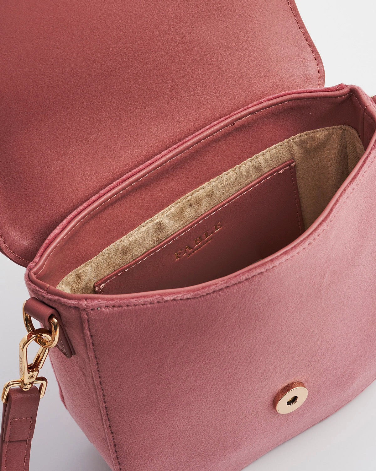 Inside of pink saddle bag with a pink and beige inside against a white background.