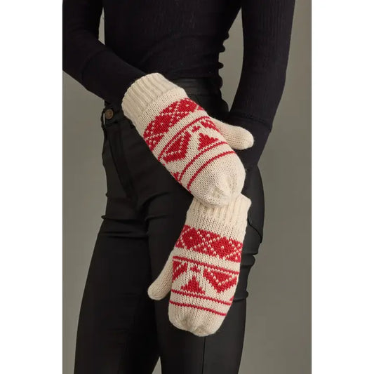 White mittens with red patterns worn by a person against a neutral background.