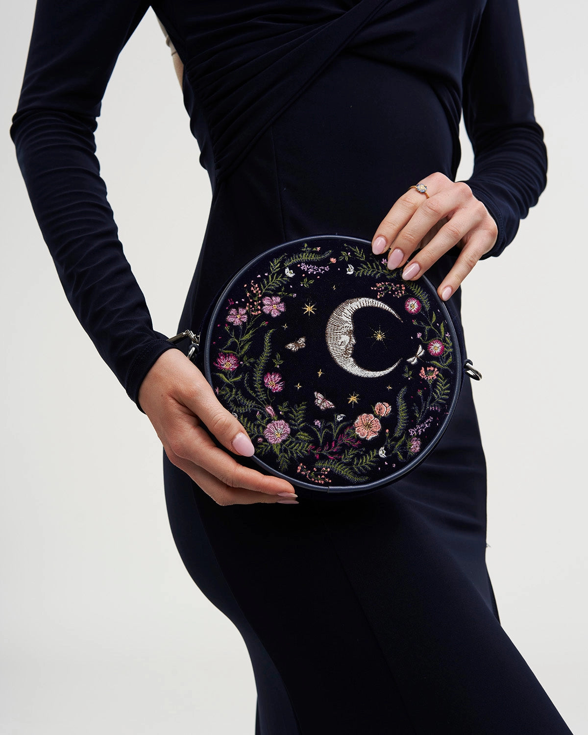 Model holding purse against their side against a white background.